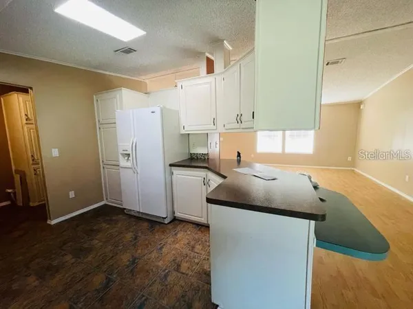 a kitchen with kitchen island granite countertop a sink and refrigerator