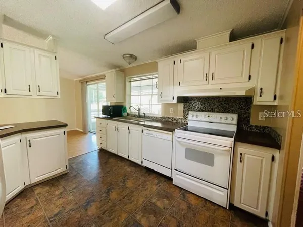 a kitchen with granite countertop white cabinets and white appliances