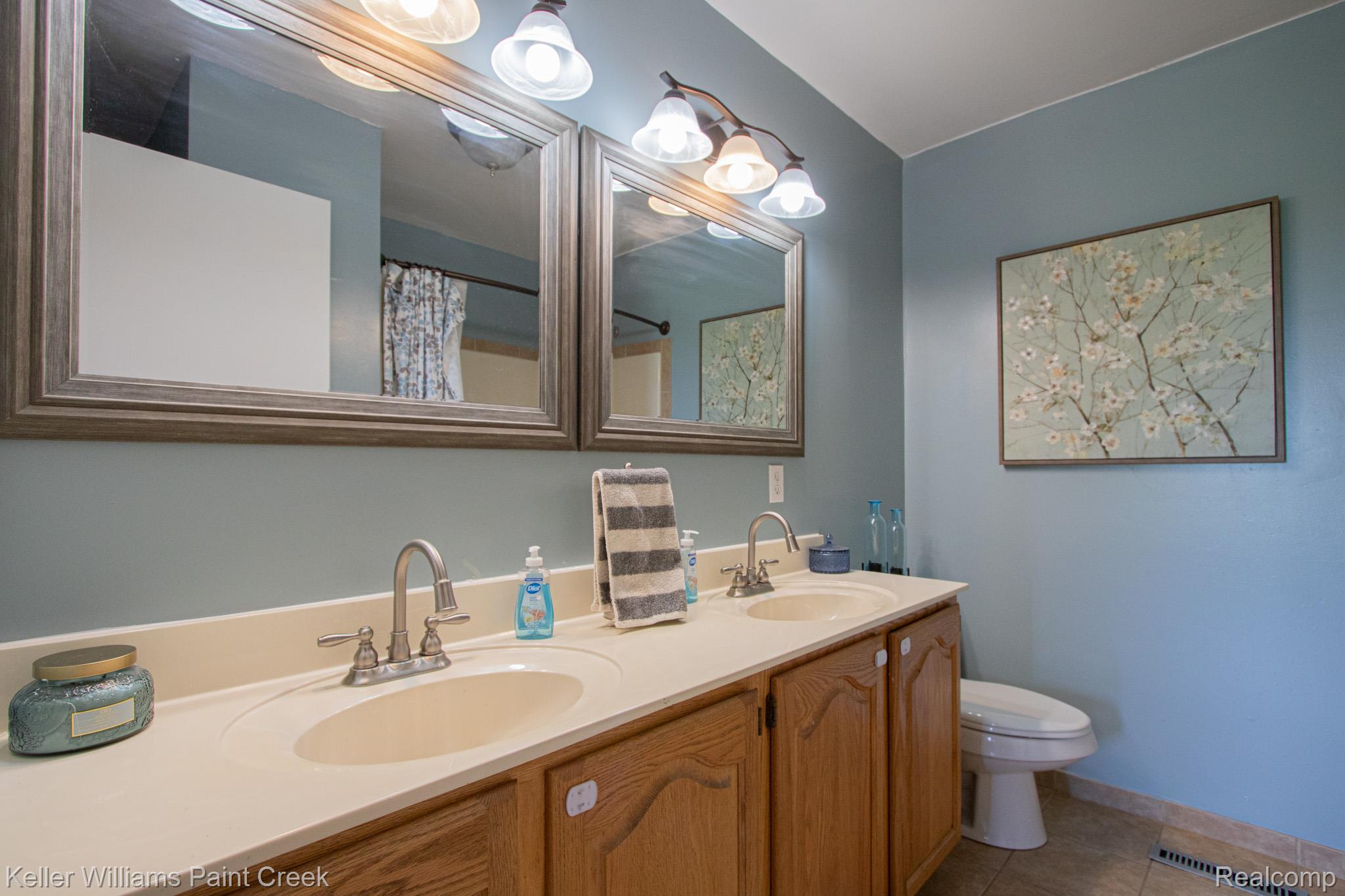 625 Howell Road Allenton, MI 48002 - Photo 18 of 46 Dual framed mirrors, double vanity with integrated sinks, and wood-finish cabinetry