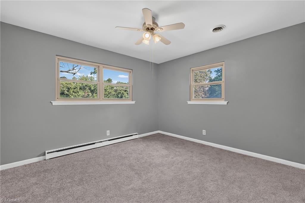 113 Green Valley Road Greensboro, NC 27403 - Photo 29 of 46 Large windows welcome natural light while offering peaceful views of the surrounding mature landscape.