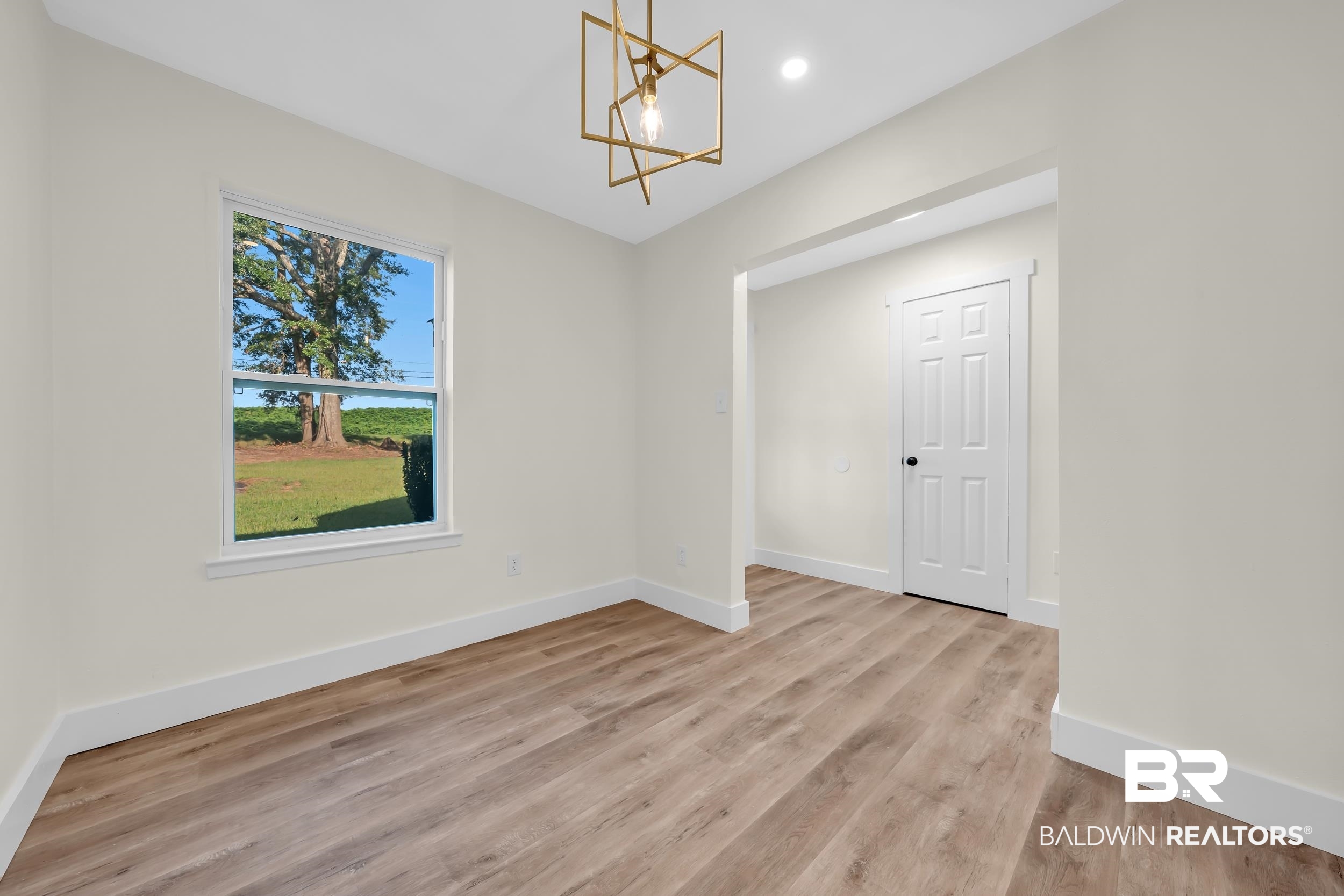 5109 McDonald Road Theodore, AL 36582 - Photo 5 of 21 Neutral wall finishes, wood-finish flooring, white trim, and a contemporary geometric pendant light fixture