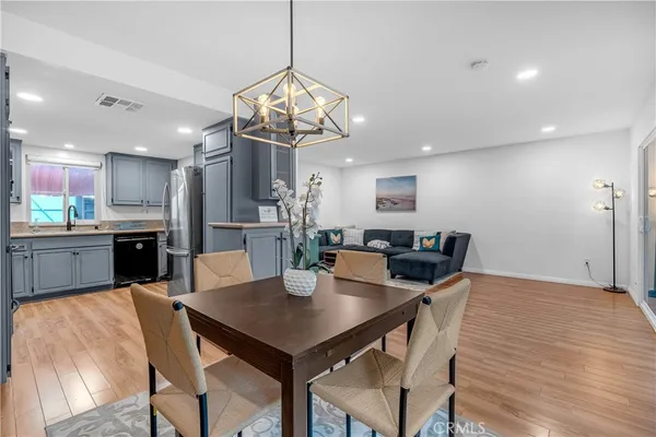 a kitchen with stainless steel appliances granite countertop a refrigerator a sink dishwasher a stove and white cabinets with wooden floor