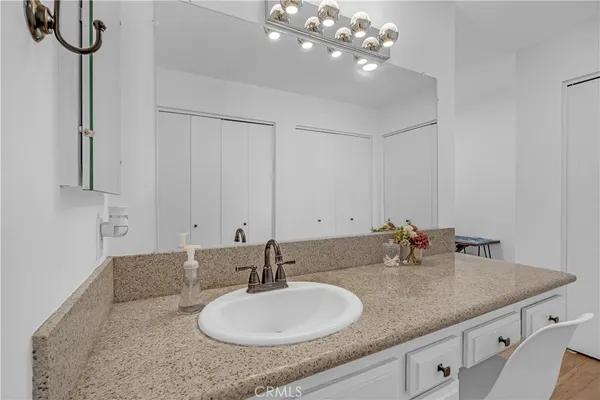 a bathroom with a granite countertop double vanity sink a mirror and shower