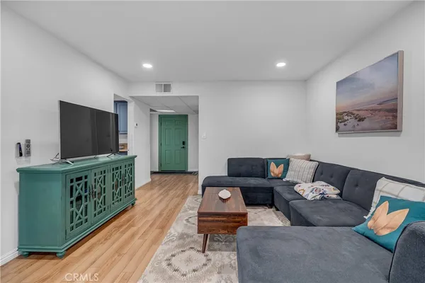 a living room with furniture wooden floor and a kitchen view