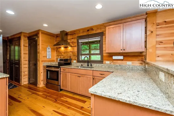 a kitchen with stainless steel appliances granite countertop wooden cabinets a oven and granite counter tops with a large window
