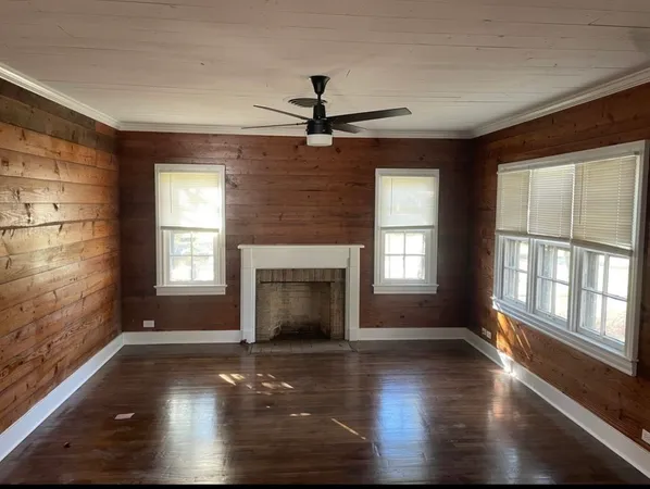 an empty room with windows and fireplace