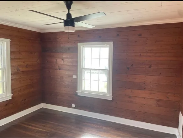 a view of empty room with wooden floor and fan