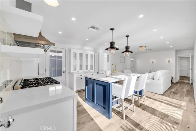 a kitchen with a stove a refrigerator and a dining table with wooden floor