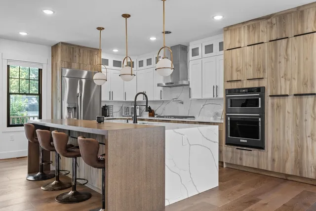 a kitchen with kitchen island granite countertop a sink a counter and stainless steel appliances