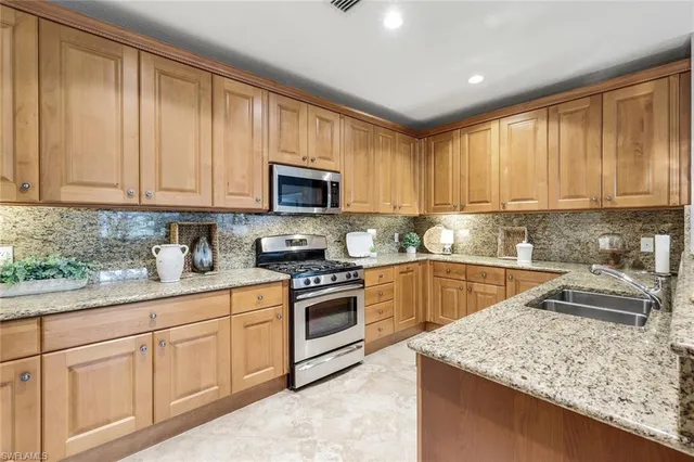 a kitchen with granite countertop white cabinets sink and stainless steel appliances