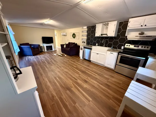 a large white kitchen with wooden floors and stainless steel appliances