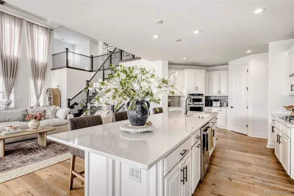 a kitchen with stainless steel appliances kitchen island granite countertop a table chairs in it and wooden floors