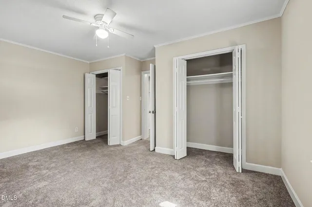 an empty room with closet and a ceiling fan