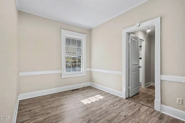 a view of an empty room with wooden floor and a window