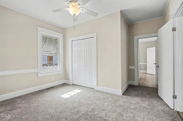 an empty room with windows and fan