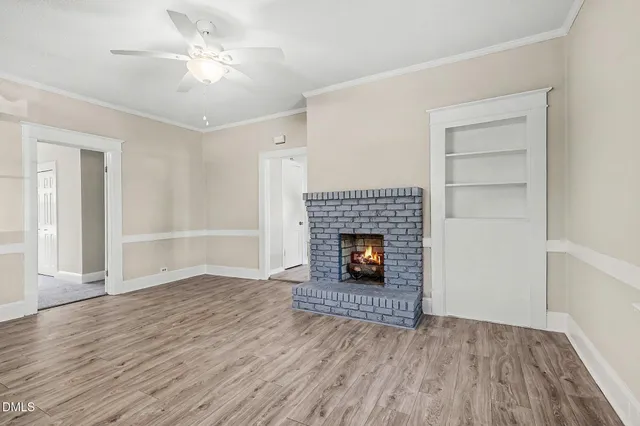 an empty room with wooden floor fireplace and window