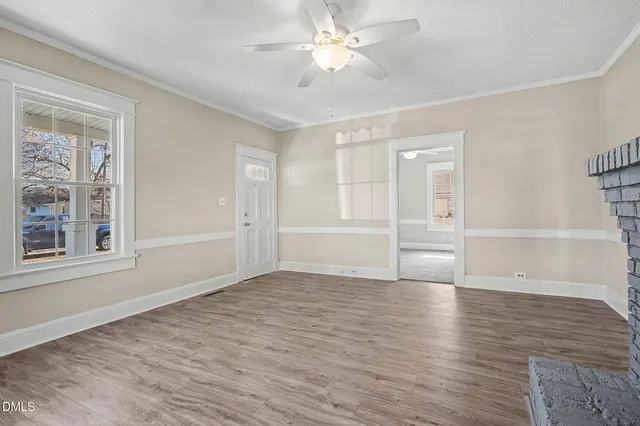 a view of empty room with wooden floor and fan