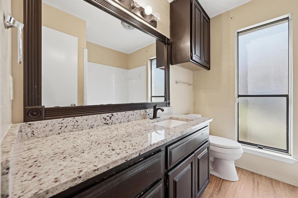 1503 North Fielder Road Arlington, TX 76012 - Photo 22 of 40 a bathroom with a granite countertop sink a toilet a mirror and shower