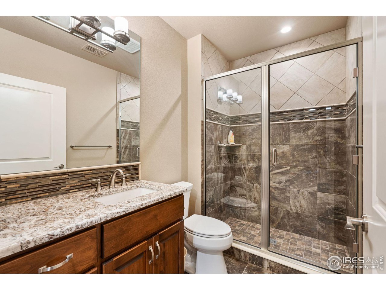 6740 Olympia Fields Court Windsor, CO 80550 - Photo 27 of 28 a bathroom with a granite countertop sink toilet and shower