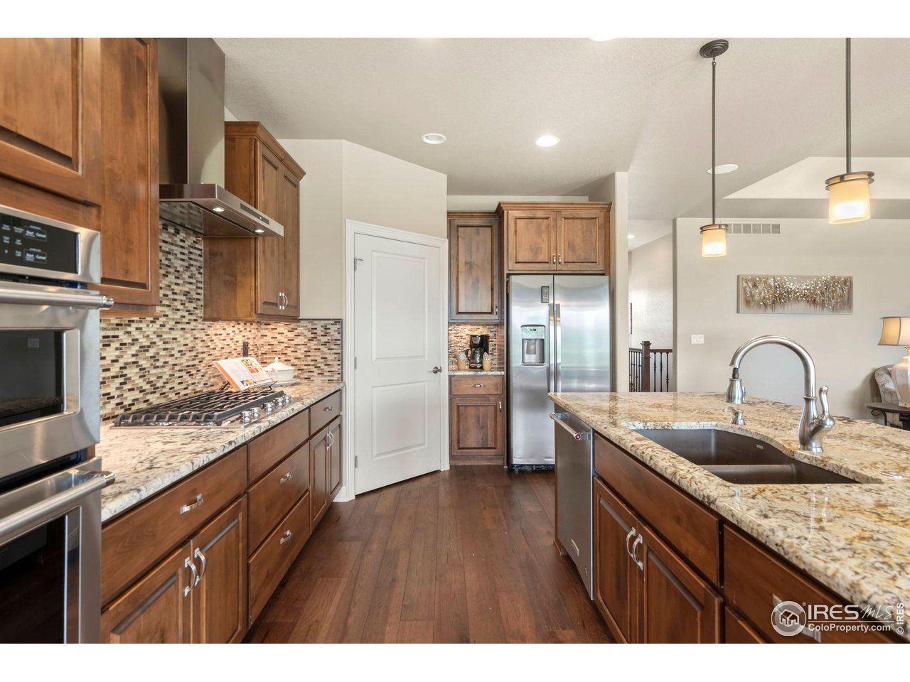 6740 Olympia Fields Court Windsor, CO 80550 - Photo 7 of 28 a kitchen with stainless steel appliances granite countertop a sink a stove and a wooden floors