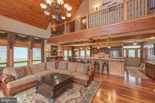 a view of a dining room and livingroom with lots of furniture wooden floor a chandelier