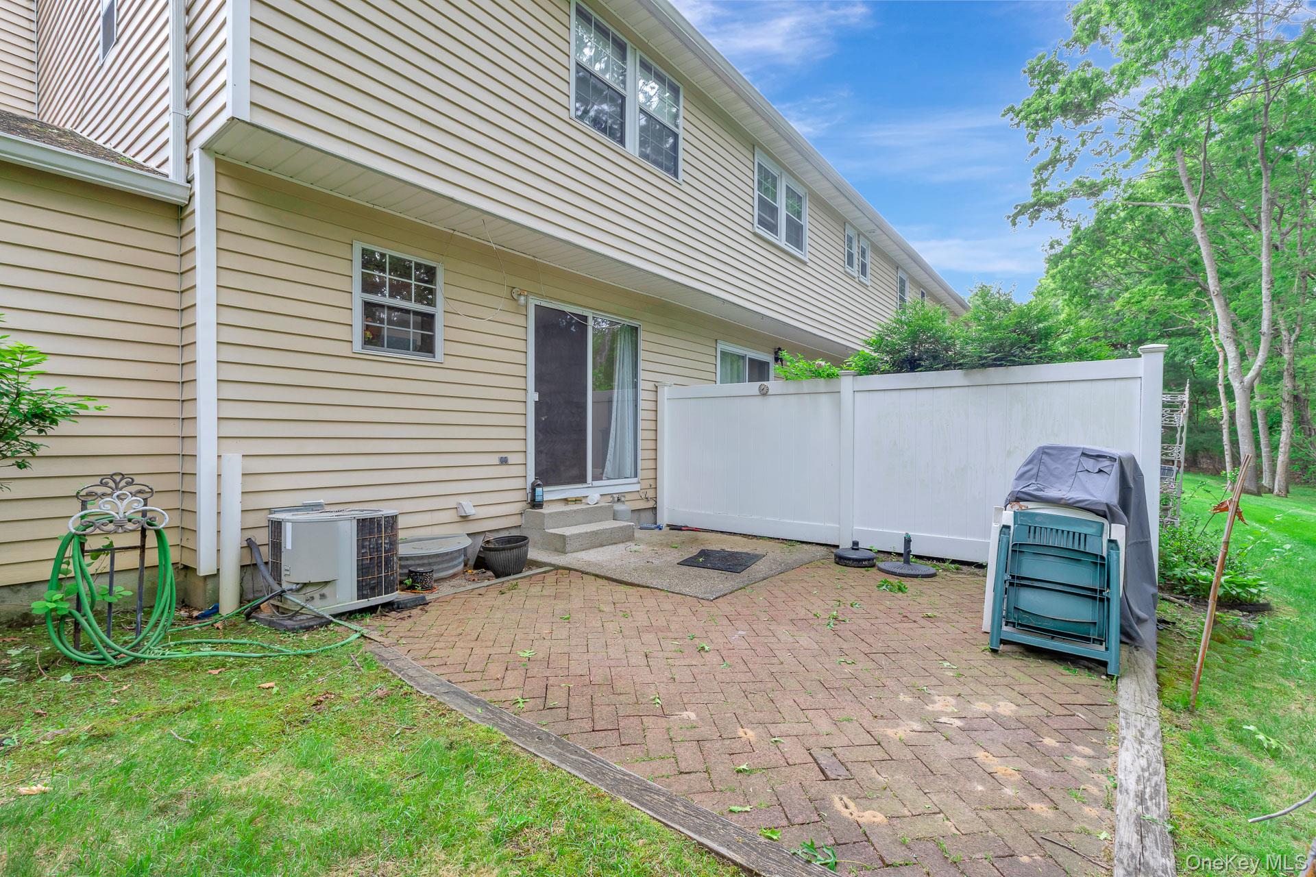 17 Stone Commons Yaphank, NY 11980 - Photo 27 of 31 Brick paver patio area featuring a privacy fence and direct access to the interior via a sliding glass door