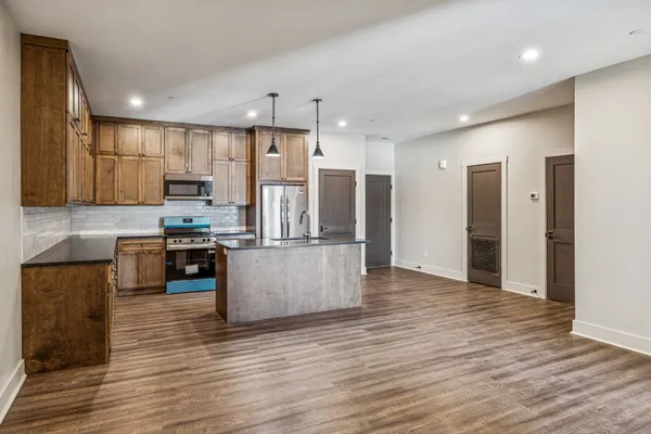 a kitchen with stainless steel appliances kitchen island sink refrigerator and cabinets