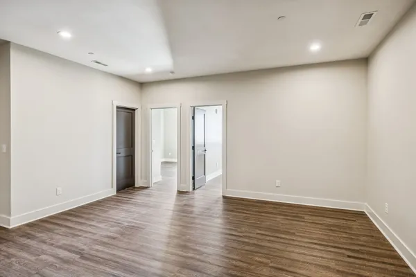 a view of an empty room with wooden floor and closet
