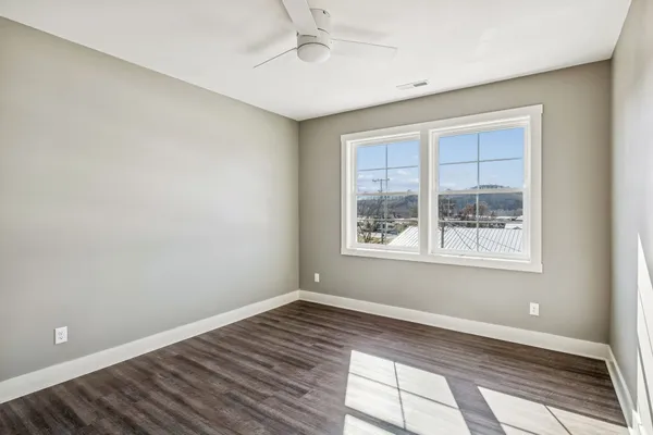 a view of an empty room with wooden floor and a window