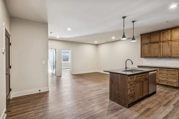 a kitchen with stainless steel appliances granite countertop a sink a stove and a wooden floors