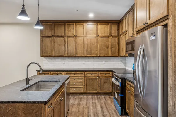 a kitchen with stainless steel appliances granite countertop a sink refrigerator and cabinets