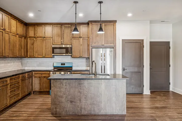 a kitchen with stainless steel appliances granite countertop a refrigerator a sink a stove and a refrigerator