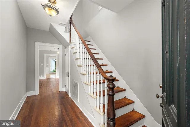 a view of an empty room with wooden floor and a ceiling fan