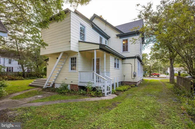 a view of an empty room with wooden floor fireplace and a window