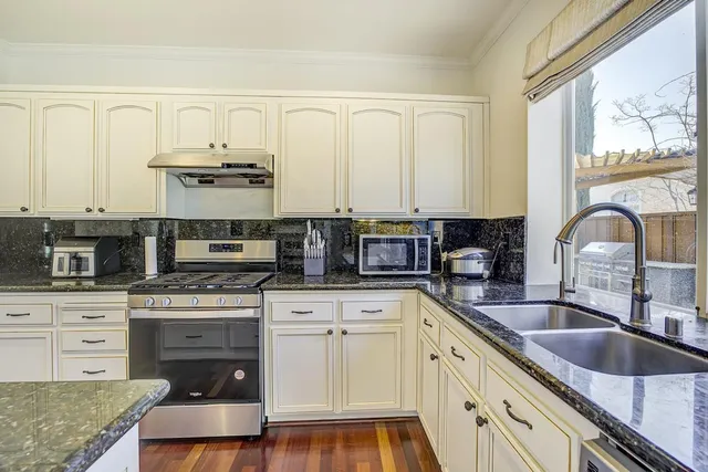a kitchen with stainless steel appliances granite countertop a stove a sink and a microwave