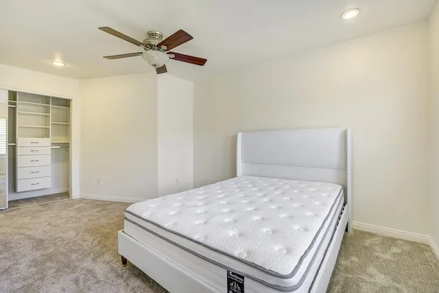a room with a bed and ceiling fan
