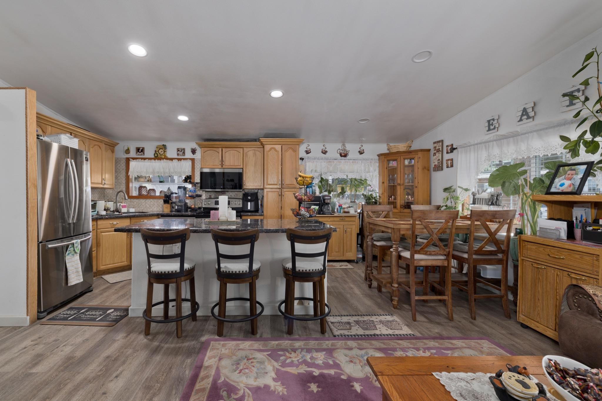 100 Ski Trails Road, Unit 10 Mammoth Lakes, CA 93546 - Photo 9 of 26 Kitchen featuring wood-finish flooring, stainless steel refrigerator, recessed lighting, wood cabinetry, and a central island with bar seating