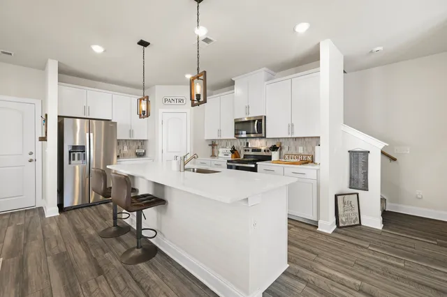 a kitchen with stainless steel appliances a refrigerator a stove a sink dishwasher and a oven with wooden floor