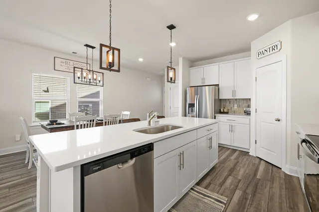 a kitchen with a sink dishwasher a stove and a refrigerator with wooden floor
