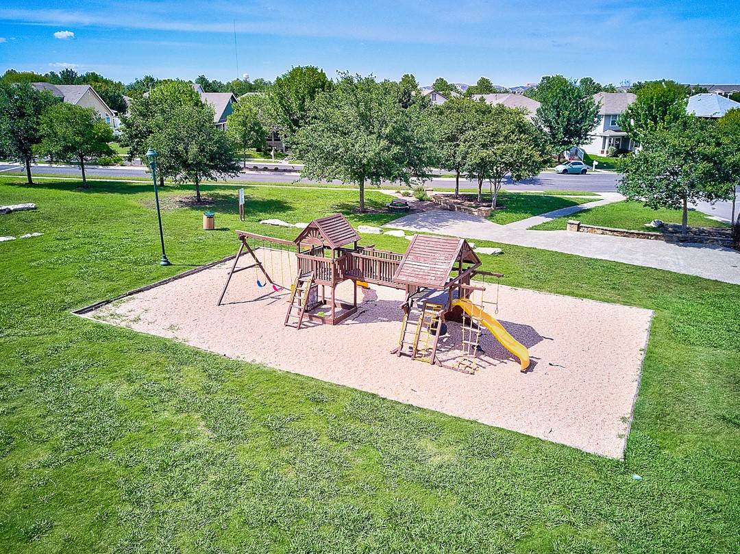 311 A Utterback Kyle, TX 78640 - Photo 36 of 40 Community playground featuring a multi-level play structure with slides and swings, set on a sand base