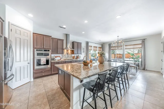 a kitchen with stainless steel appliances granite countertop a stove top oven a sink dishwasher a dining table and chairs with wooden floor