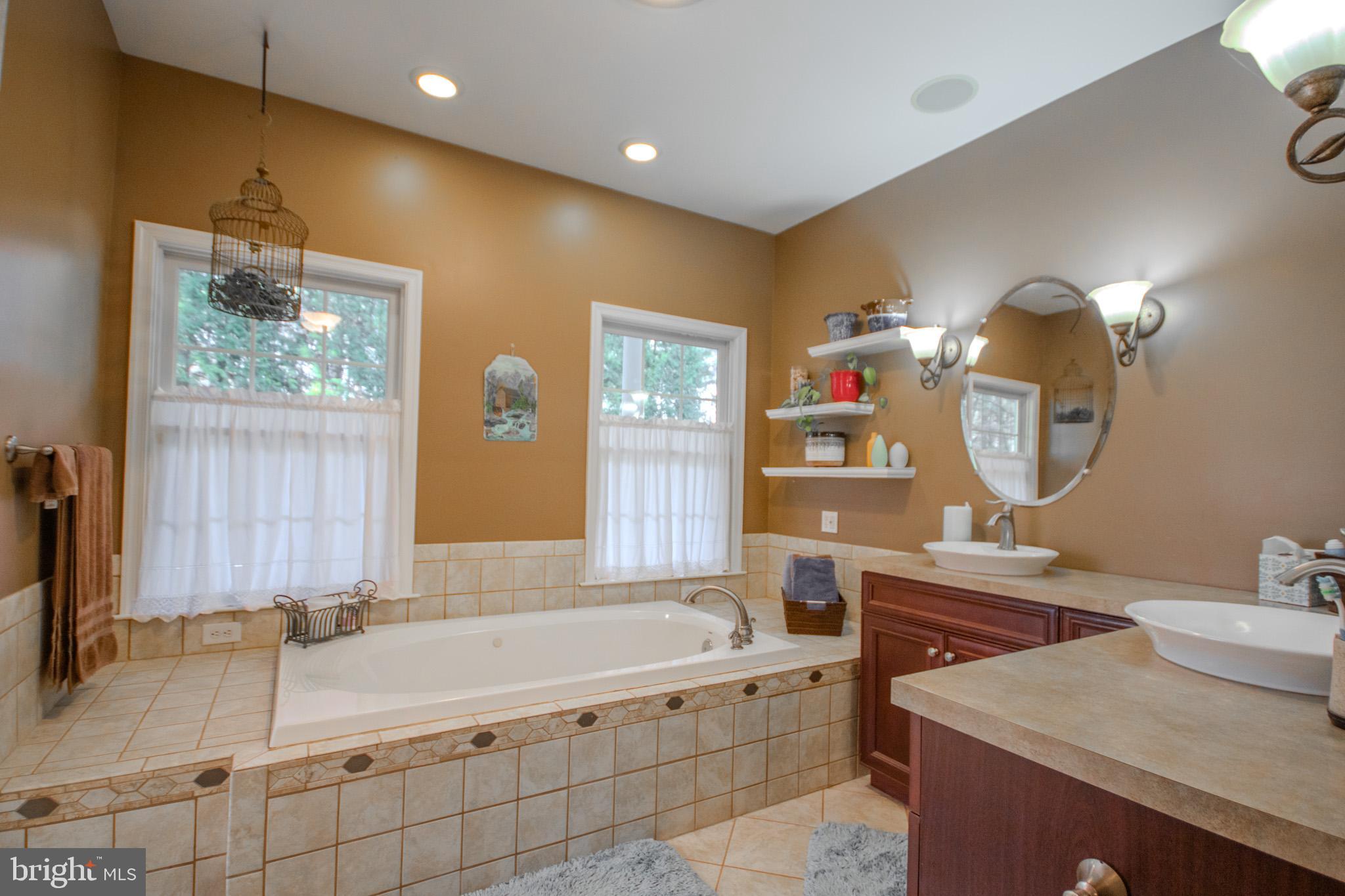 7395 Cherry Walk Road Hebron, MD 21830 - Photo 28 of 61 a spacious bathroom with a tub a double vanity sink and mirror