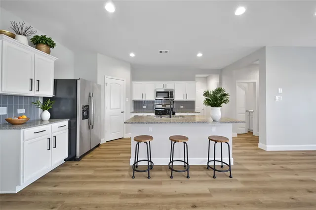 a kitchen with granite countertop white cabinets and stainless steel appliances
