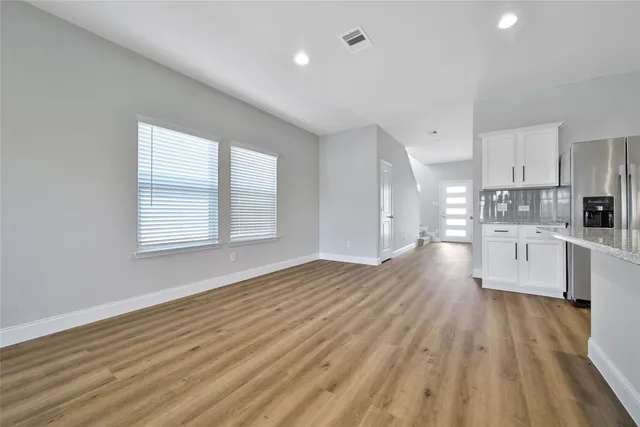a large white kitchen with wooden floors and white stainless steel appliances