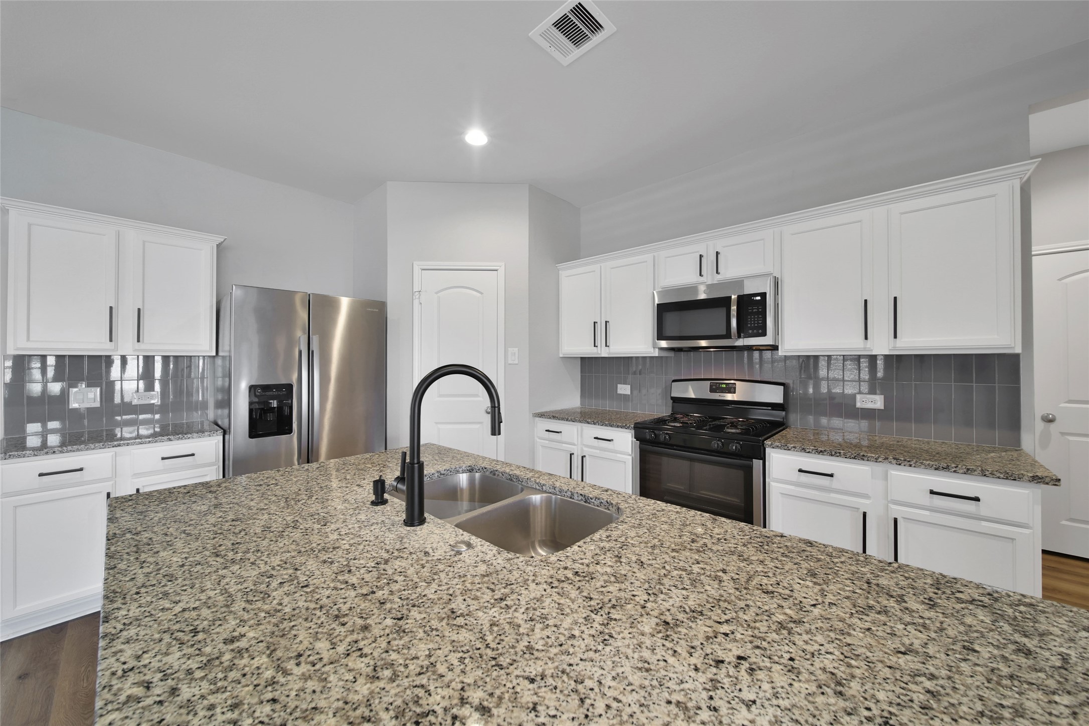2415 Sutton Hollow Court Spring, TX 77373 - Photo 10 of 40 a kitchen with stainless steel appliances granite countertop a sink a stove top oven a counter space and cabinets