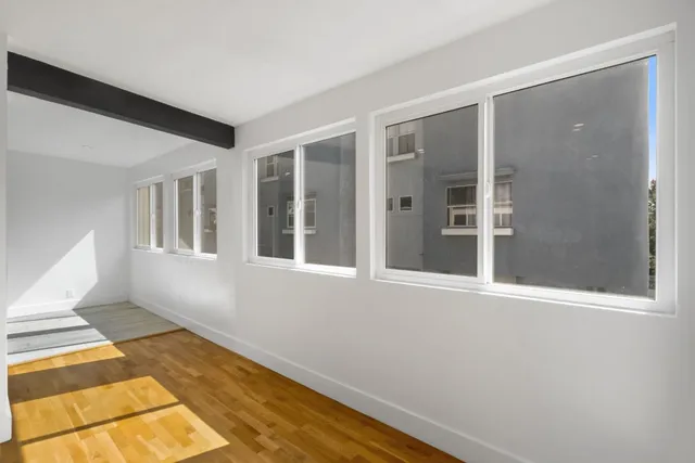 a view of an empty room with wooden floor and a window