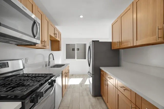 a kitchen with granite countertop a refrigerator stove and sink