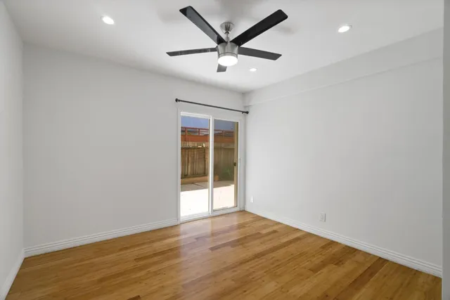 an empty room with wooden floor and ceiling fan
