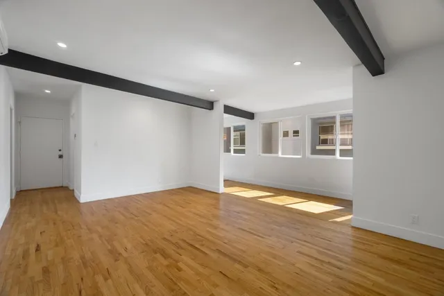 a view of an empty room with wooden floor and a window