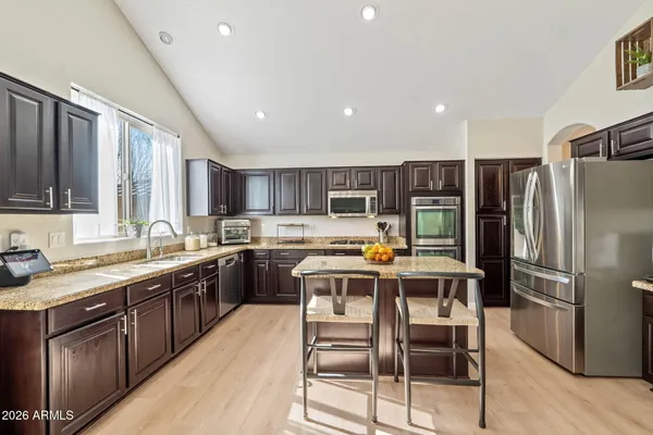 a kitchen with stainless steel appliances granite countertop a table chairs sink and cabinets
